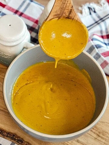 the finished Carolina gold BBQ sauce in a bowl with a spoon