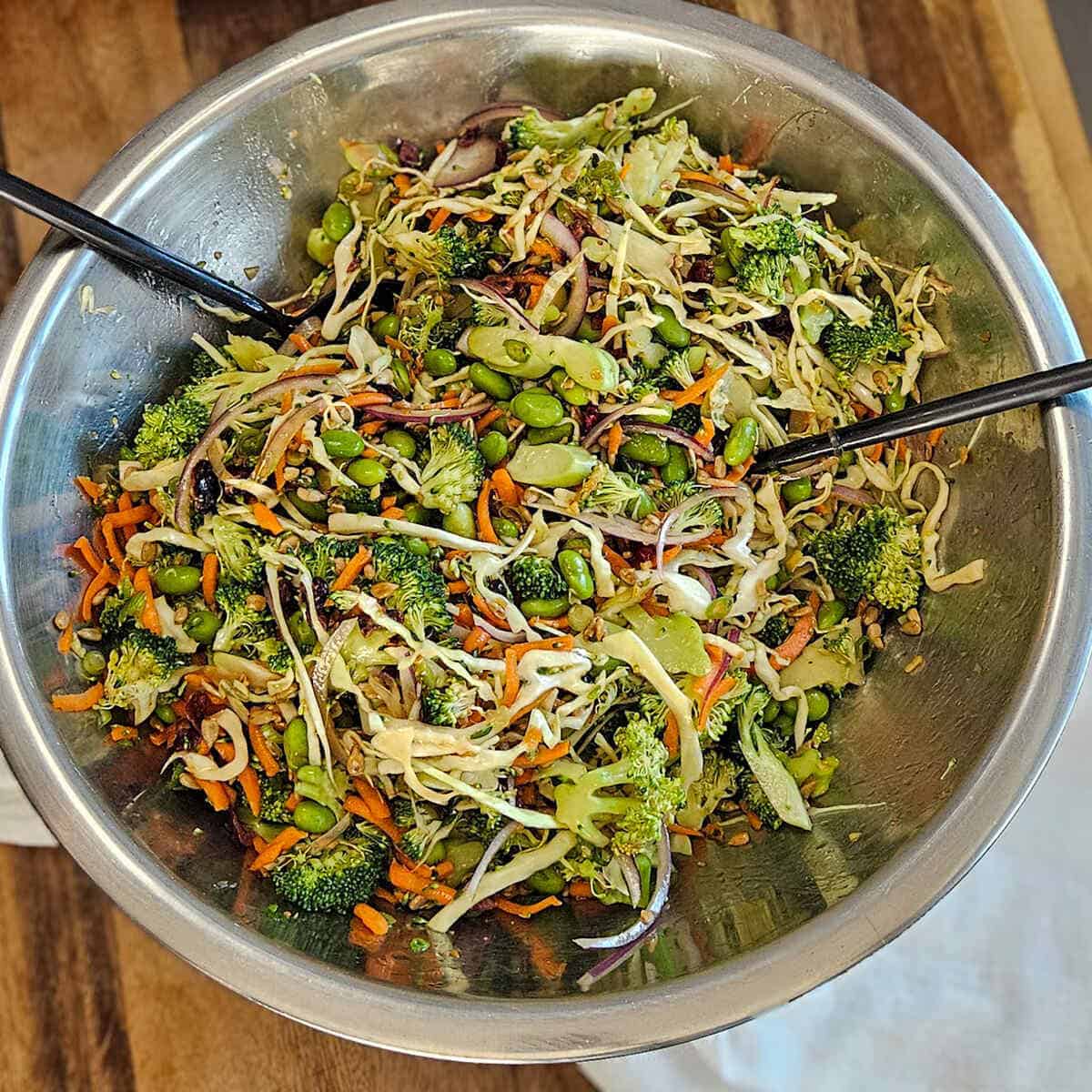 Mixing the ingredients for the easy Asian broccoli crunch salad in a large mixing bowl with a serving spoon and fork.
